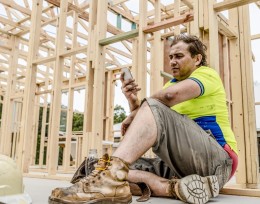 Image of a man at a work site sitting down on his mobile phone