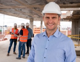 Image of a smiling man in a hard hat at a high-rise building site