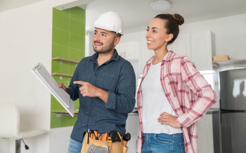 Image of a builder at site with his female client looking at plans